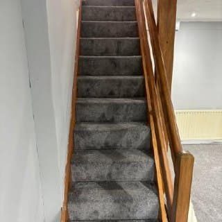Carpeted staircase with oak handrails on both sides, looking upward